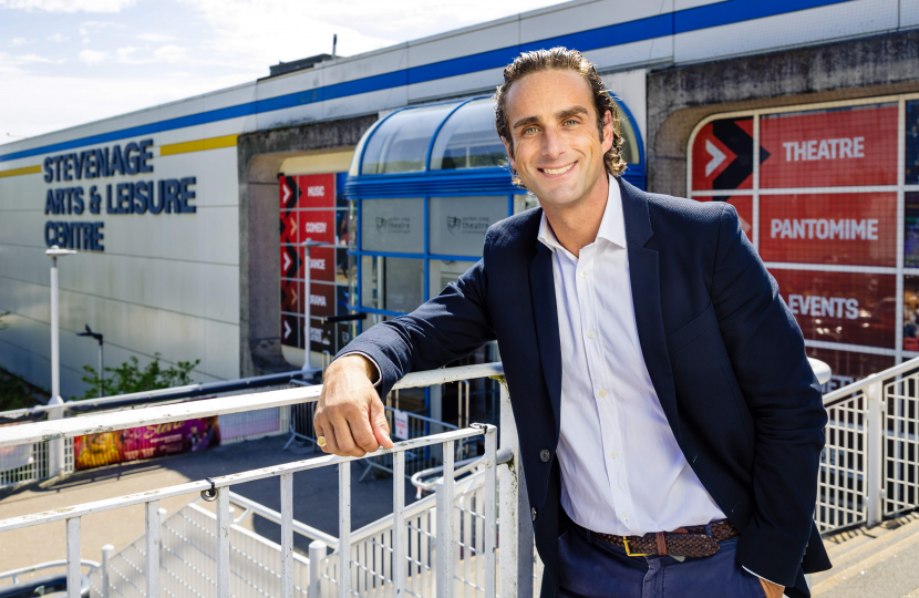 Alex Clarkson dressed smartly and smiling at the camera. Stevenage Leisure Centre is in the background.