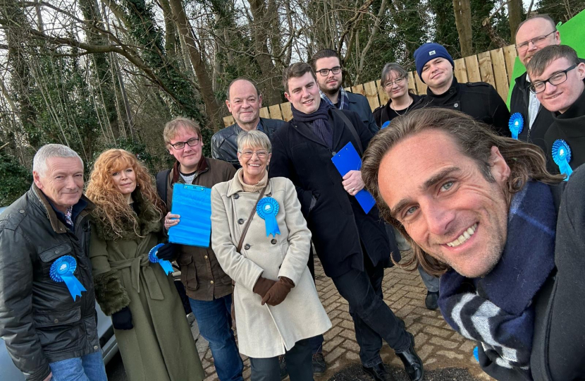 Alex Clarkson with a team of Conservative activists, there is woodland in the background.