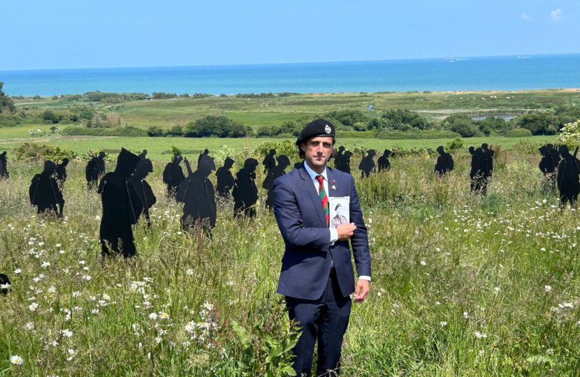 Alex visiting Normandy. He is stood in a field with 'Tommys' in the background