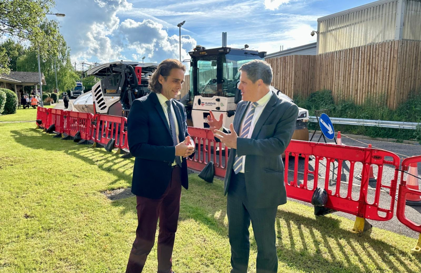 Alex talking with a Minister from the Department for Transport. They are stood in front of some building works and a tarmacking machine.