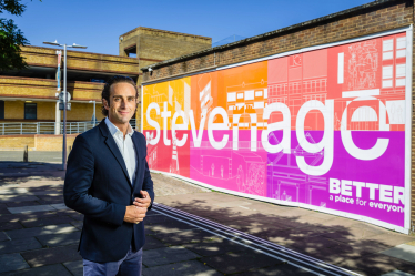 Alex Clarkson standing in front of the large 'Stevenage' sign in Stevenage town centre