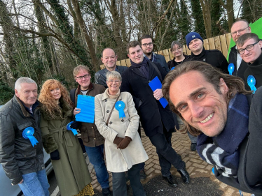 Alex Clarkson with a team of Conservative activists, there is woodland in the background.