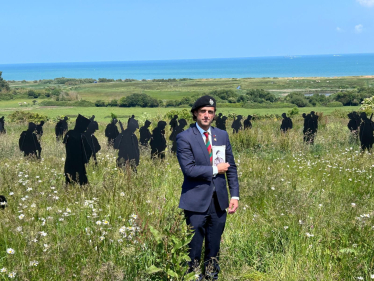 Alex visiting Normandy. He is stood in a field with 'Tommys' in the background